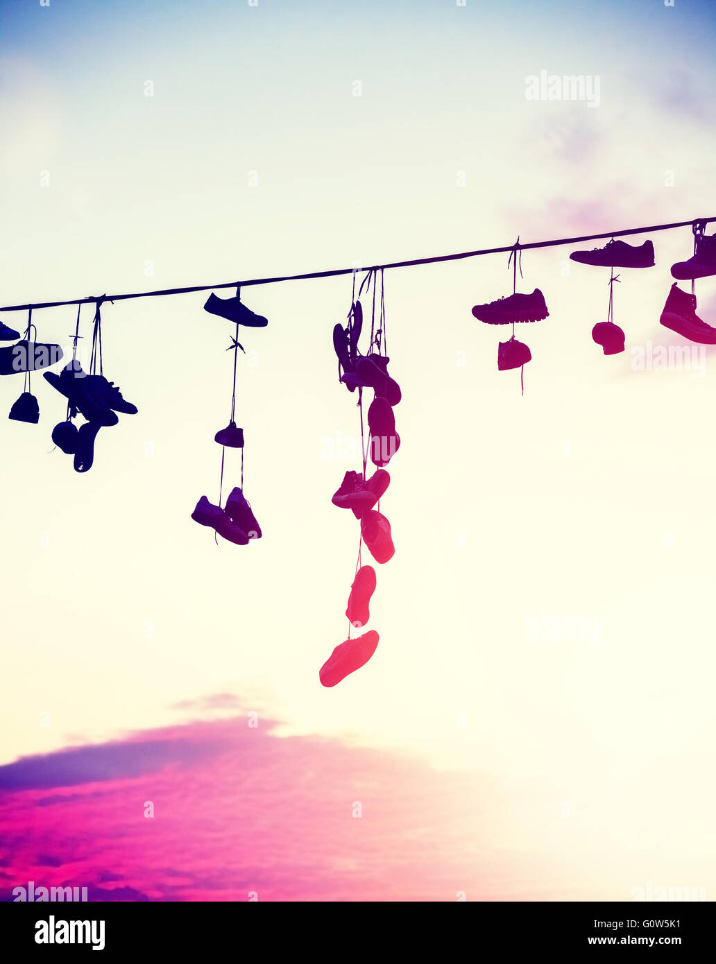 Silhouettes de tons Vintage shoes hanging sur le câble au coucher du soleil, la rébellion adolescente concept. Banque D'Images
