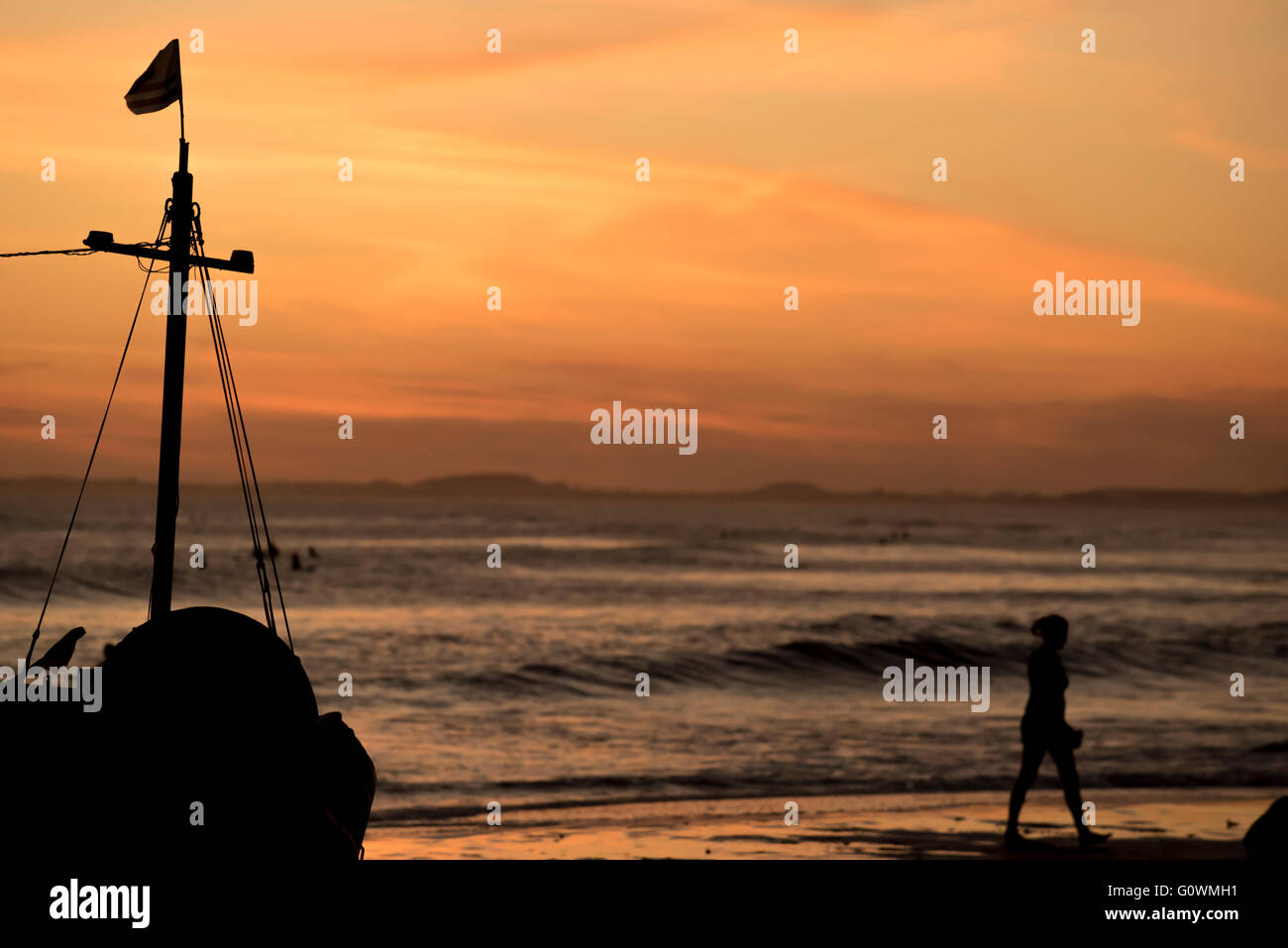 La baie de la plage au coucher du soleil, les vacances d'été paysage avec bateau à voile silhouette et les touristes. Banque D'Images