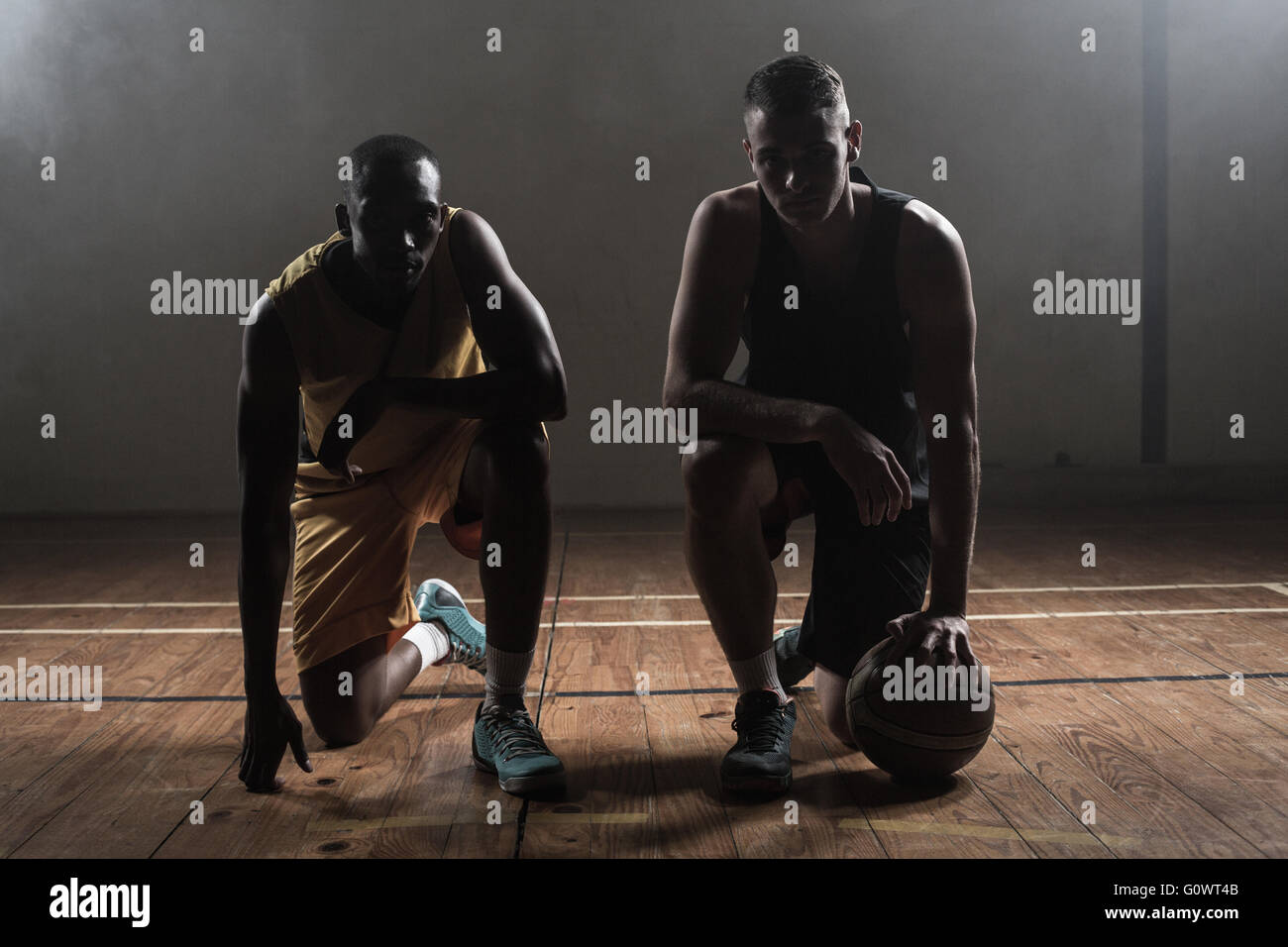 Portrait de joueurs de basket-ball qui posent sur leurs genoux Banque D'Images