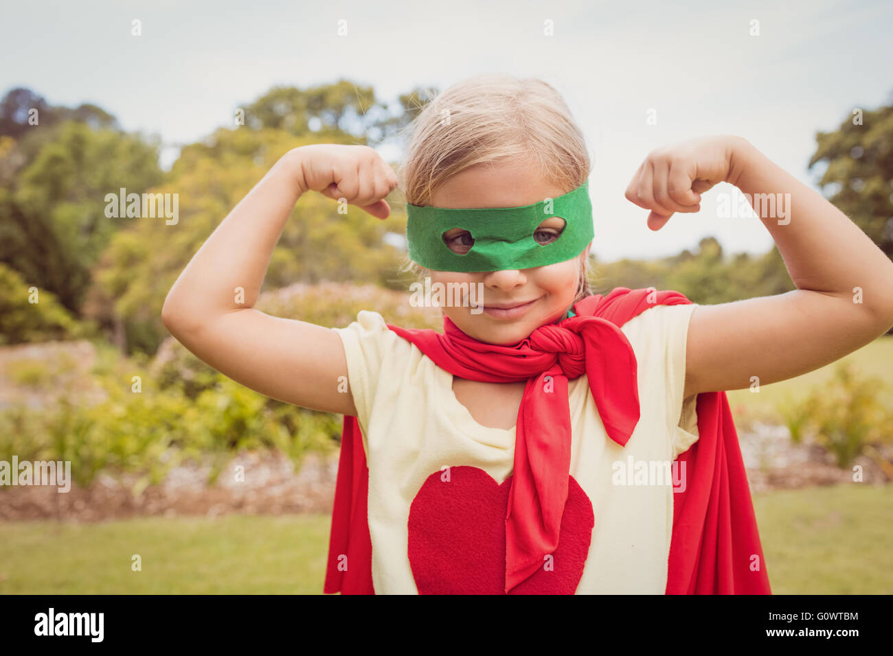 Little girl wearing superhero costume partie biceps Banque D'Images