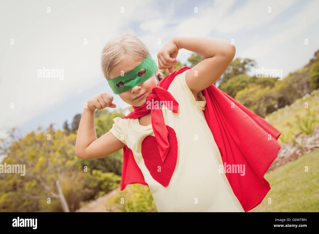 Little girl wearing superhero costume partie biceps Banque D'Images