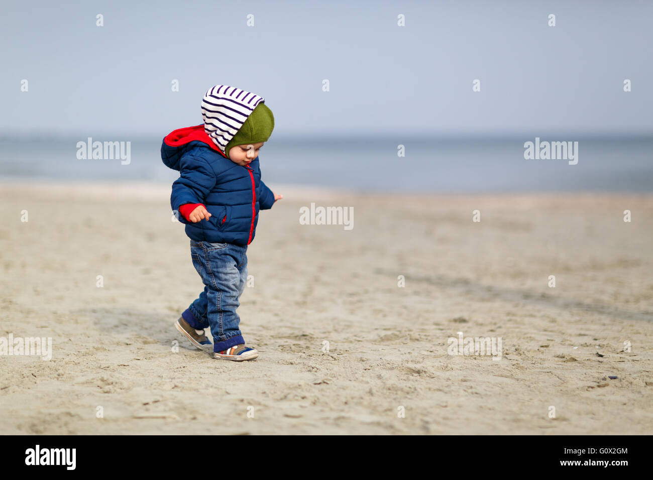 Petit garçon sur une journée ensoleillée sur une plage en hiver. Banque D'Images