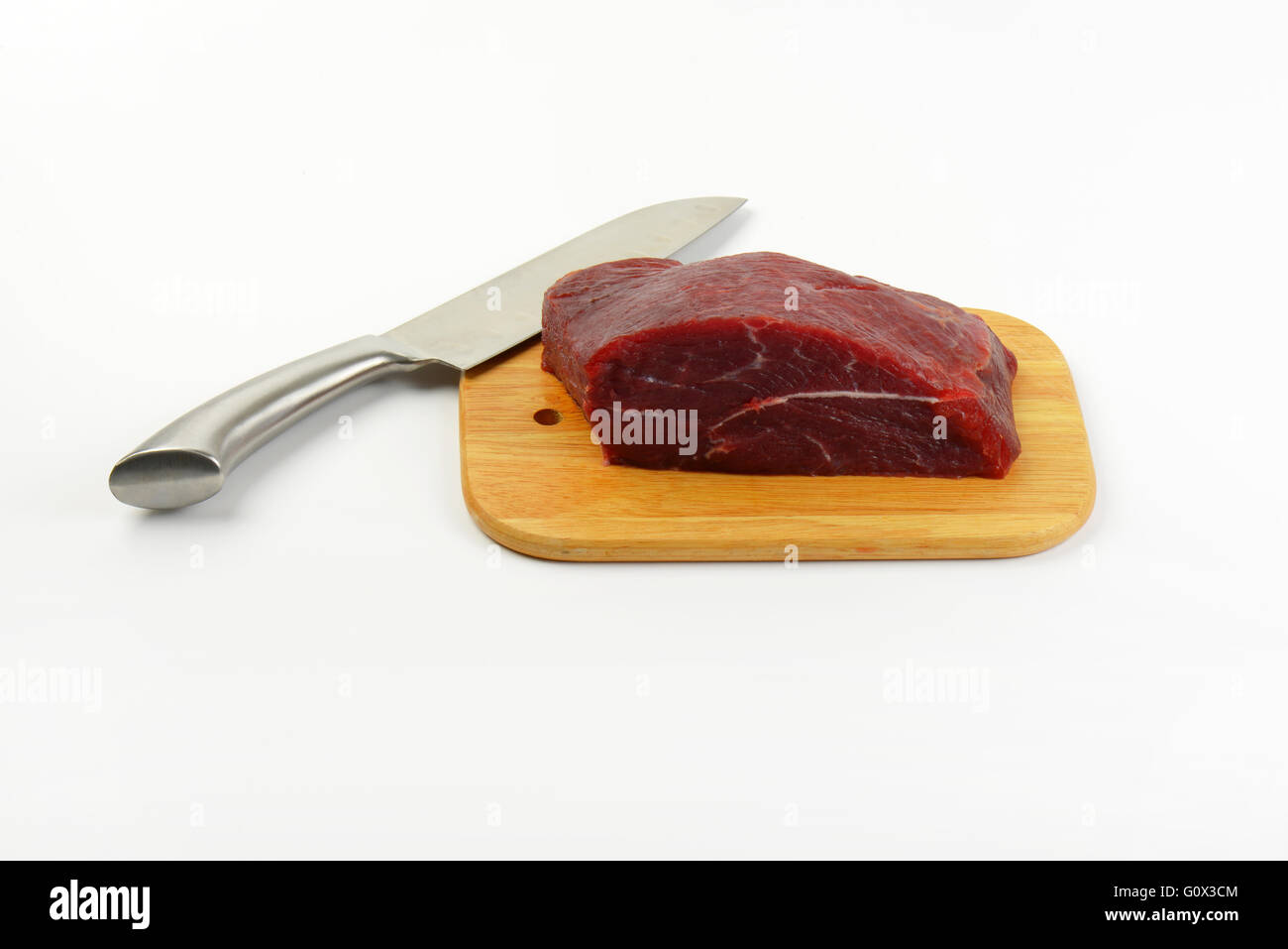 Morceau de viande de boeuf et d'un couteau sur une planche à découper en bois Banque D'Images