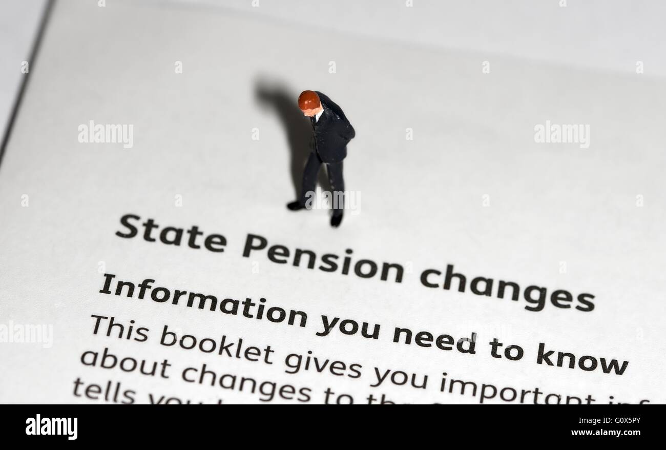 Une figurine miniature businessman looking down sur une brochure d'information sur les modifications au régime de pension de l'état Banque D'Images