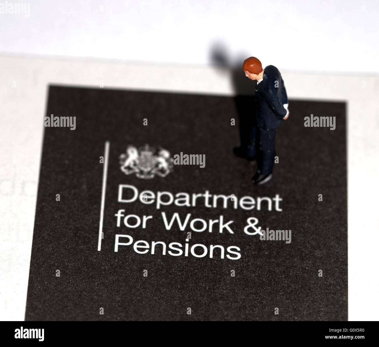 Une figurine miniature businessman looking down sur une brochure d'information pour le ministère du travail et des pensions Banque D'Images