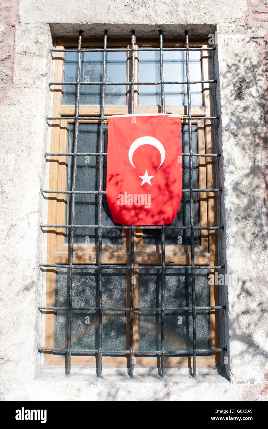 Le drapeau de la Turquie pendu à une fenêtre avec des barres (Istanbul, Turquie). Banque D'Images