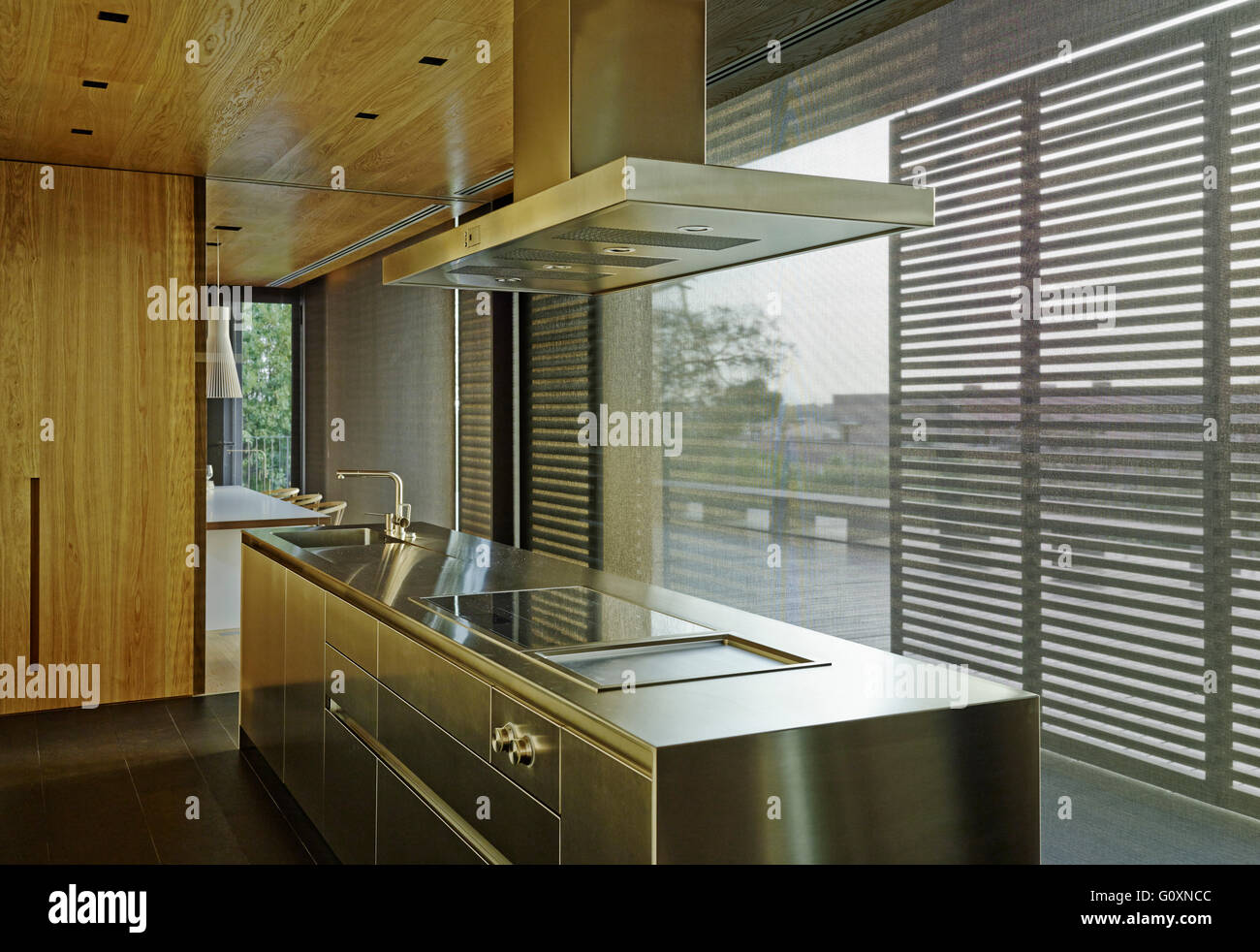 PX House, La Garriga, Espagne. Cuisine moderne avec station de travail en acier inoxydable et de baies vitrées. Cloison de verre séparant une table à manger. Banque D'Images