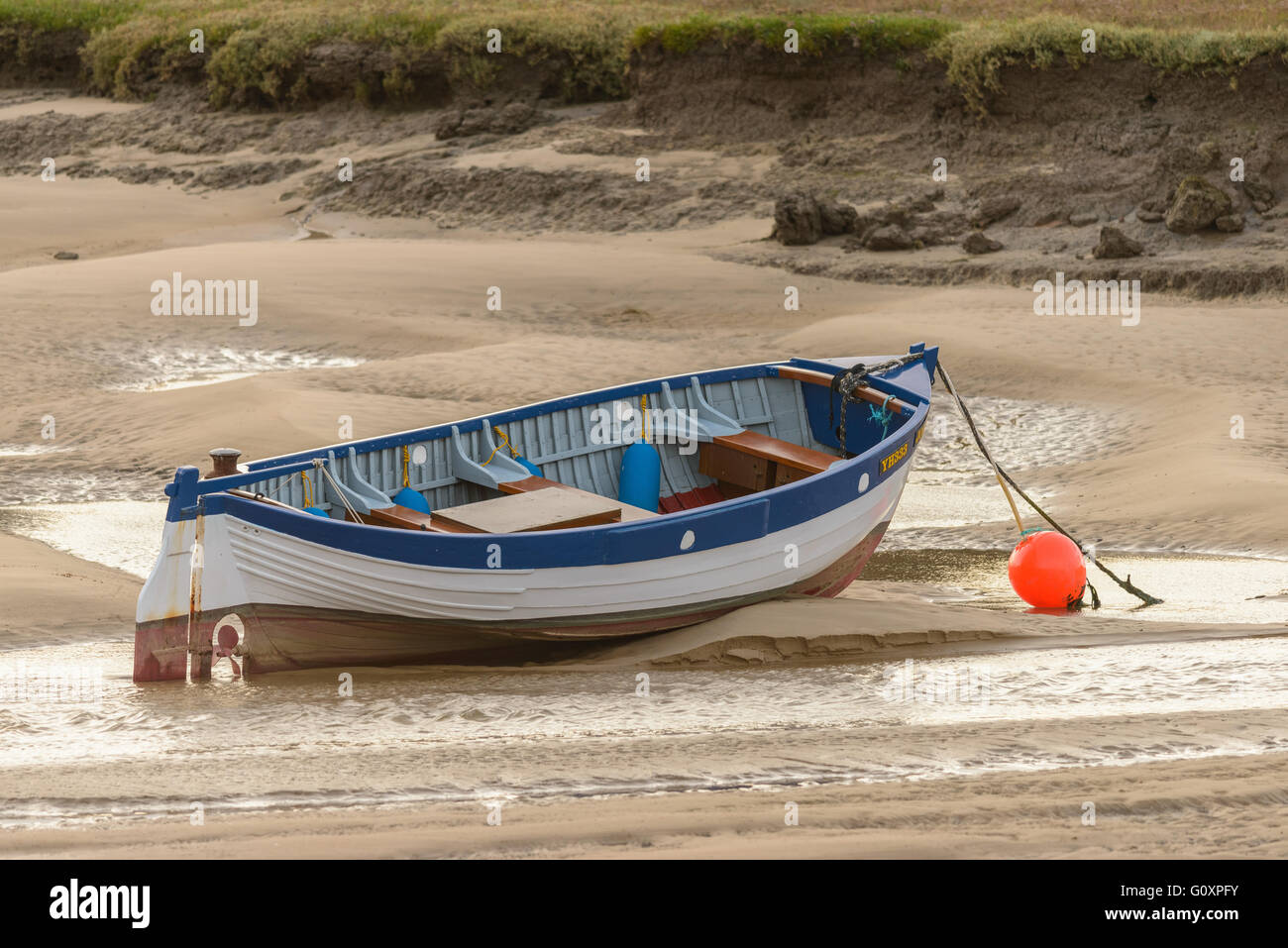 Un petit bateau à rames sur des sables à marée basse sur la côte de Norfolk, Angleterre Banque D'Images