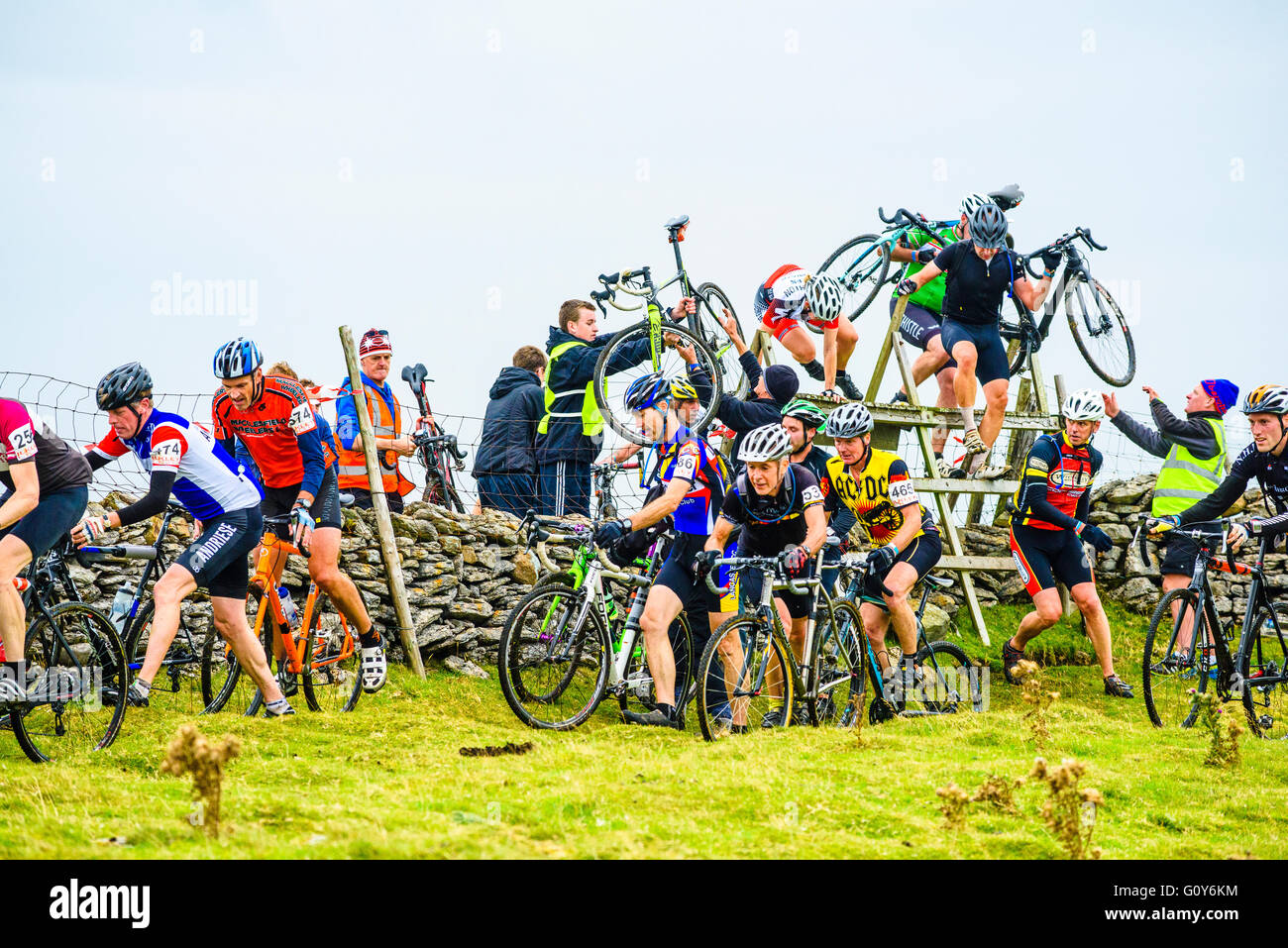 Riders corss une stile sur Ingleborough dans les trois pics 2015 course de cyclocross, un événement annuel sur trois montagnes Yorkshire Banque D'Images