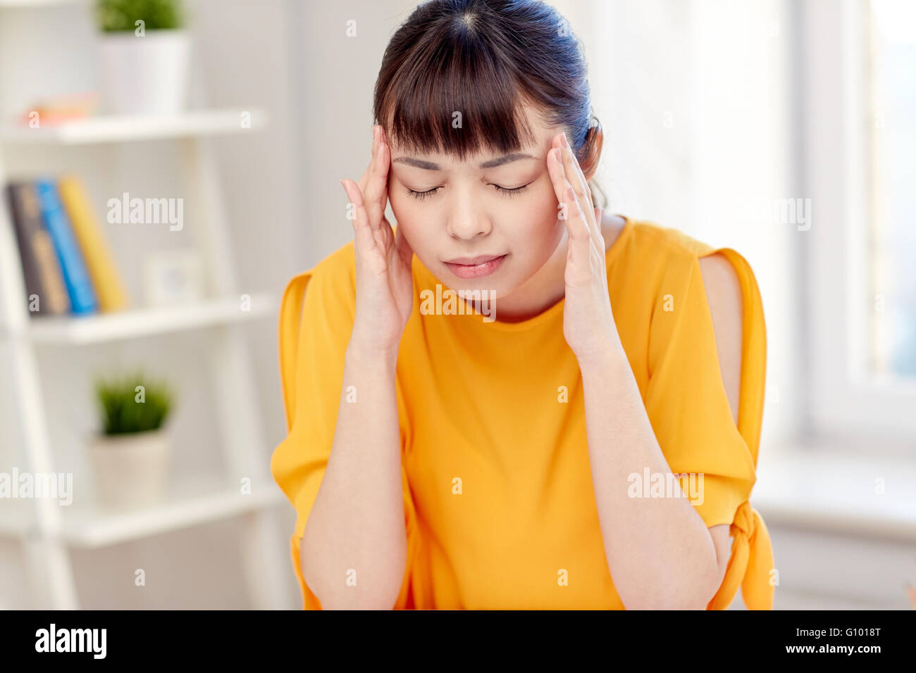 Femme asiatique fatigué souffrant de maux de tête à la maison Banque D'Images