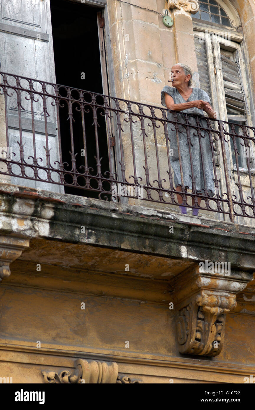 Vieille femme fumant un cigare dans le balcon dans un immeuble en mauvais état dans la Habana Vieja, Cuba. Banque D'Images