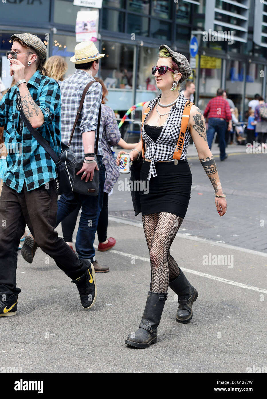 Mode de rue à Brighton jeune femme portant une jupe noire courte bottes noires et une télévision cap Banque D'Images