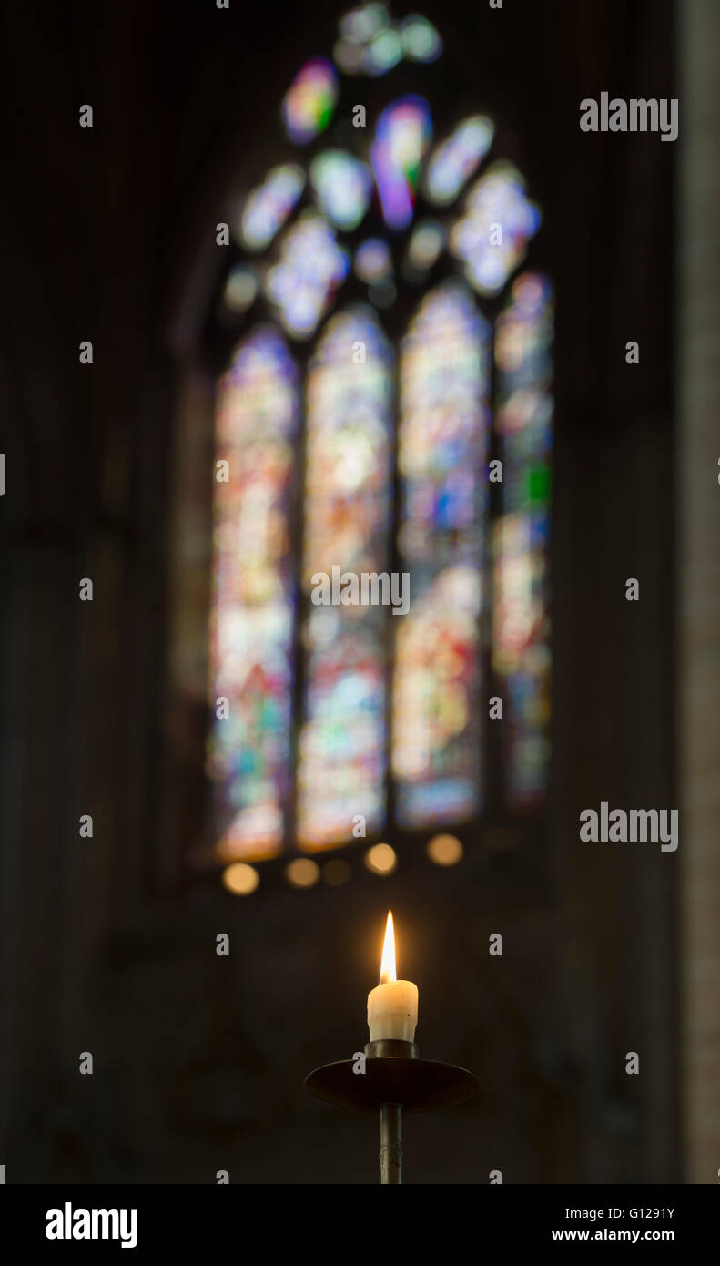 Seul cierge allumé en face d'un vitrail moderne à Ely, selectve focus. Cambridgeshire, Angleterre Banque D'Images
