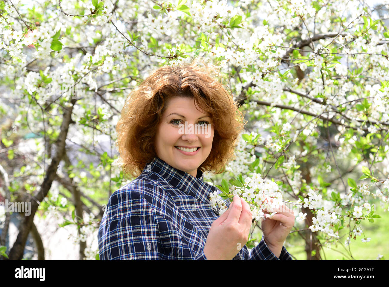Portrait de femme aux cheveux bouclés dans cherry jardin au printemps Banque D'Images