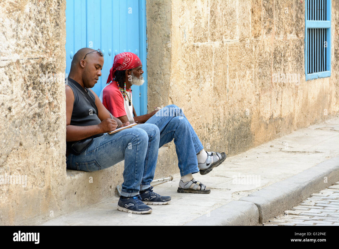 Un dessinateur de rue et un homme âgé avec un cigare, vous détendre sur une porte dans la Vieille Havane, La Havane, Cuba Banque D'Images
