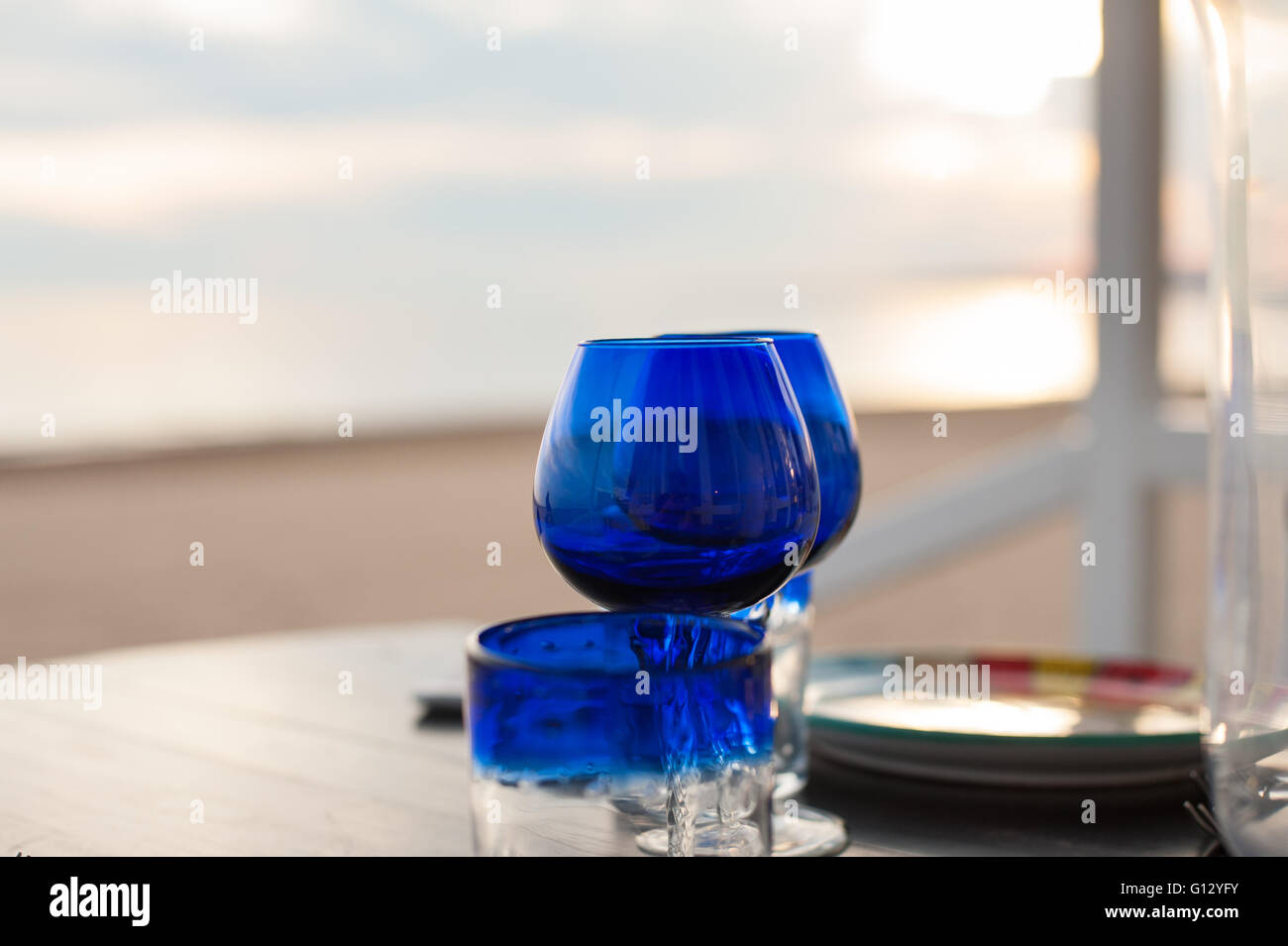 Gros plan sur la table verres bleu concept d'amour avec coucher de soleil romantique sur la plage en arrière-plan Banque D'Images