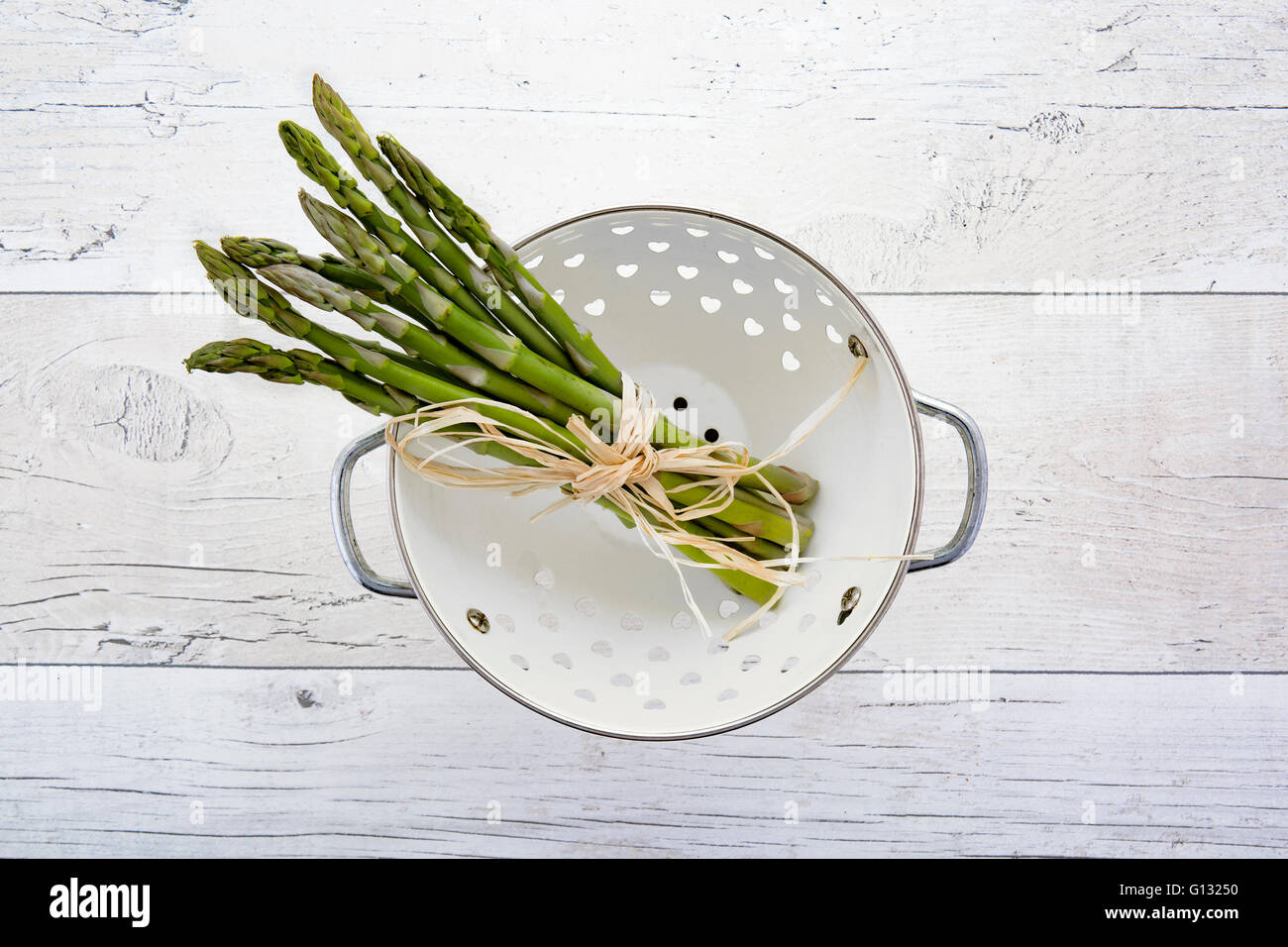Les asperges vertes dans une passoire sur le vieux fond de bois Banque D'Images