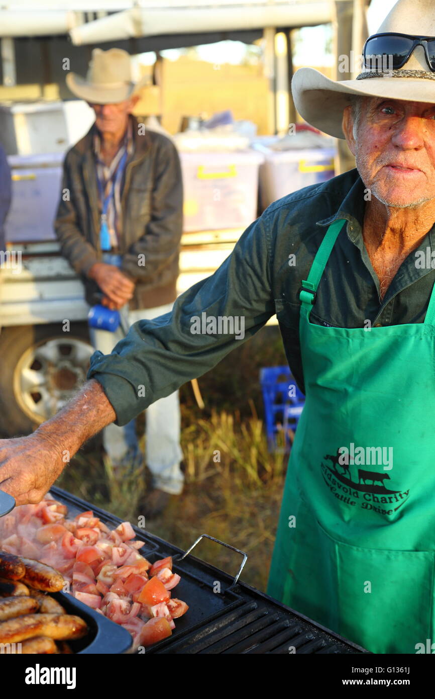 Un homme d'âge mûr petit-déjeuner de cuisson sur barbecue portant un chapeau  de cowboy et un tablier vert. Un autre cowboy regarde en arrière-plan Photo  Stock - Alamy