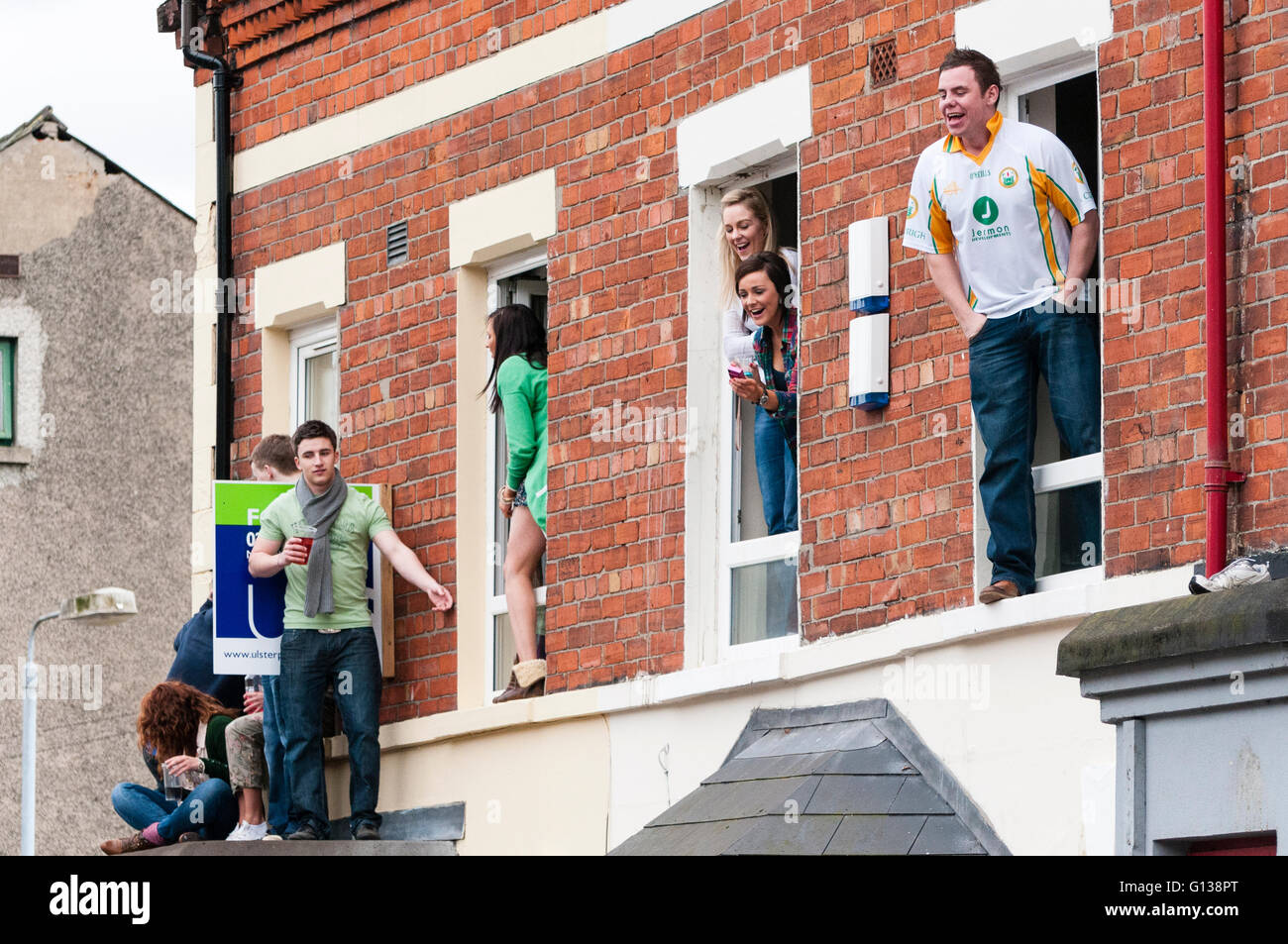 Belfast, Irlande du Nord. 17 mars 2011 - Les élèves célèbrent le Jour de la Saint Patrick par escalade de fenêtres et baie vitrée sur les toits des maisons louées dans les lieux saints de Belfast. Banque D'Images