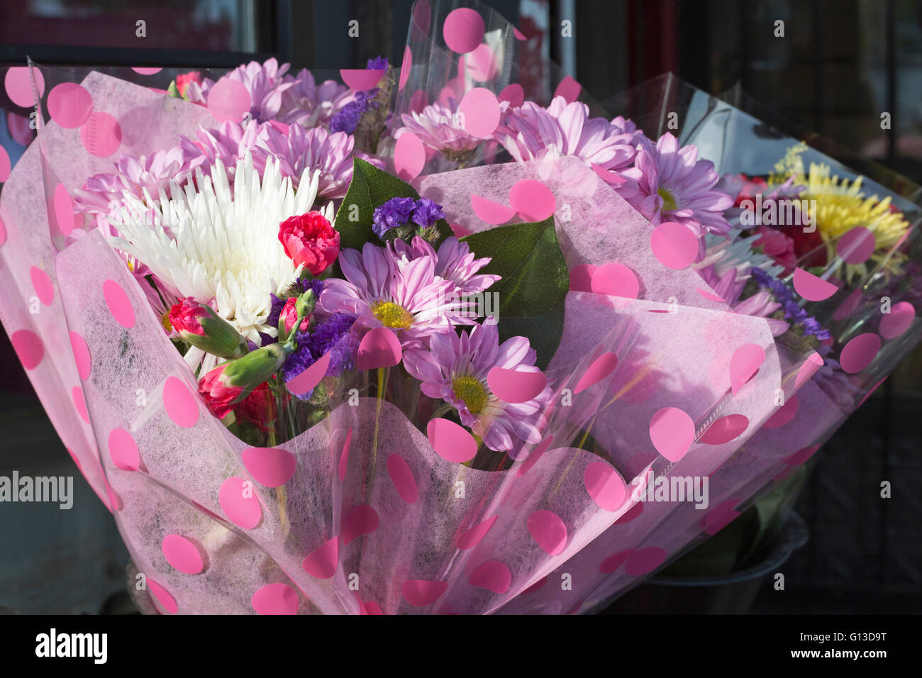 Cadeau bouquet de fleurs fraîches enveloppé de papier à pois rose à vendre sur le marché local de Bridgeland Banque D'Images