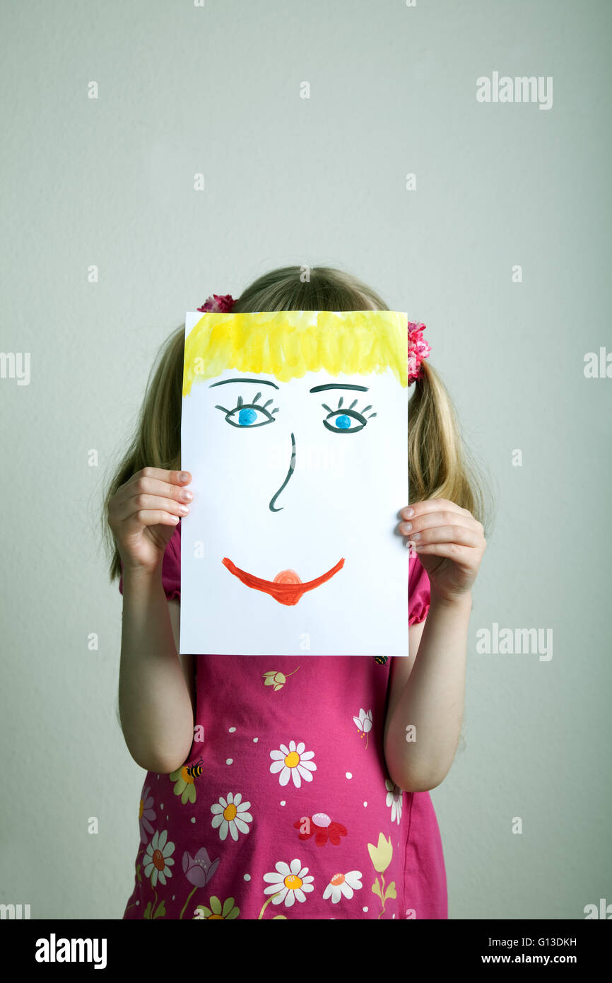 Petite fille avec masque peint avec heureux et triste visage Banque D'Images