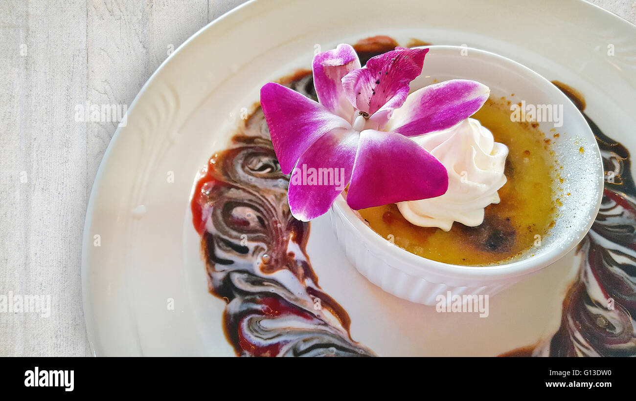 Fantaisie crème brûlée dessert avec orchidée rose comestible. Banque D'Images