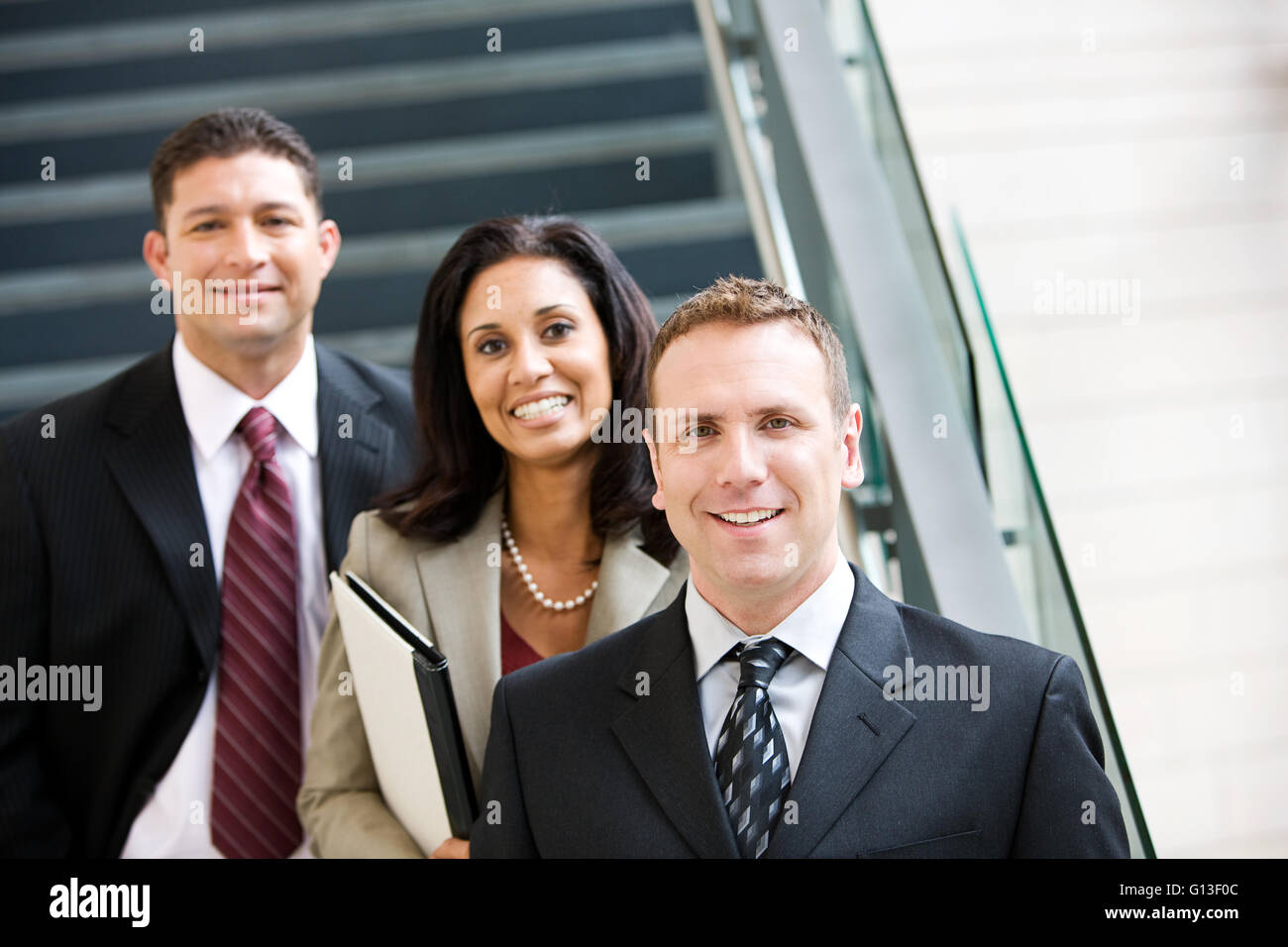 Businesspeople dans diverses poses par l'escalier en verre. Banque D'Images