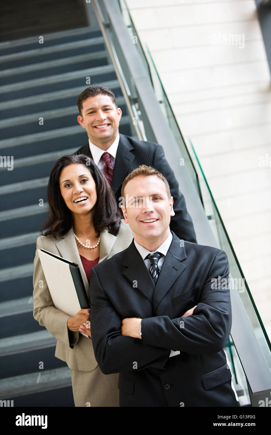 Businesspeople dans diverses poses par l'escalier en verre. Banque D'Images