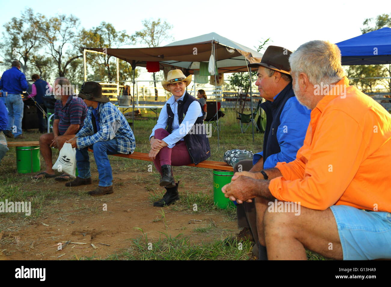 Un groupe de campeurs rural chat sur bancs de planches pendant qu'ils attendent pour le petit-déjeuner. Banque D'Images