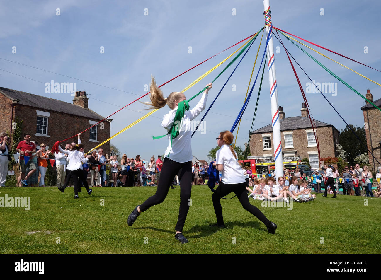 Les enfants de la danse autour d'un mât à Aldborough peut jour festival dans le Nord du Yorkshire, UK. Banque D'Images