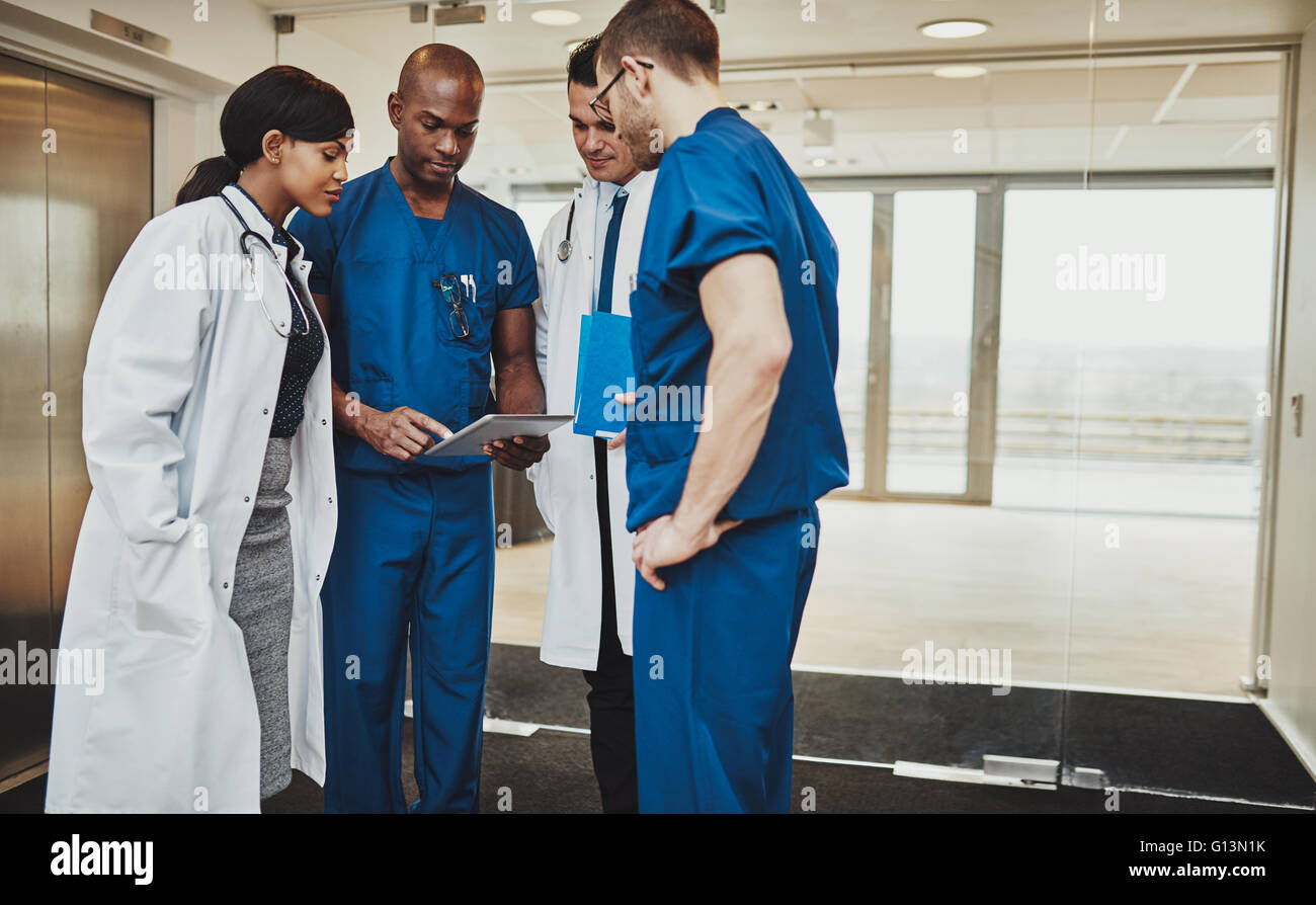 L'équipe multiraciale de médecins de discuter d'un patient à la tablette, à des médecins et chirurgiens Banque D'Images