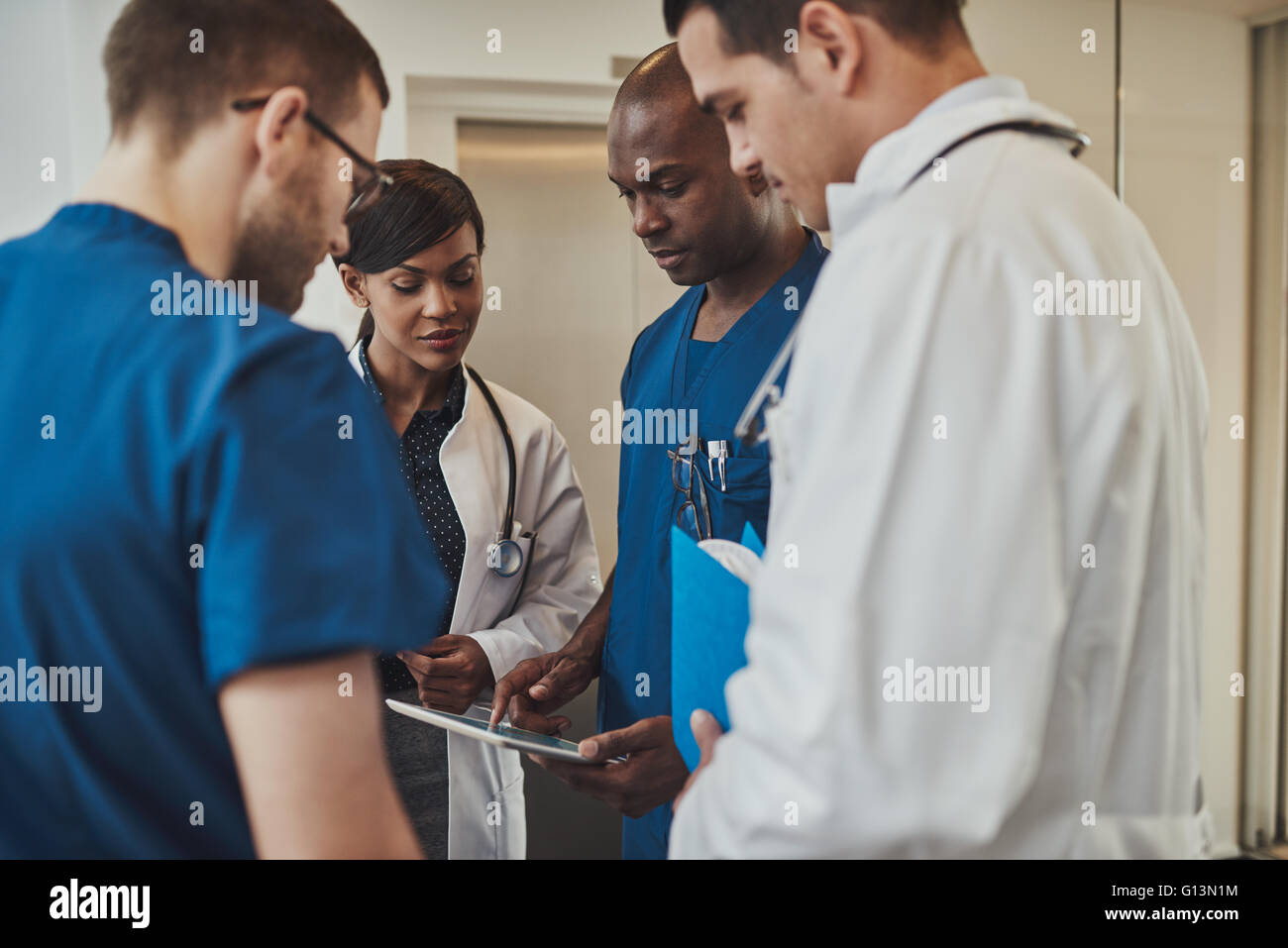 Groupe diversifié de médecins ayant une urgence multiraciale permanent de discussion regroupés en étroite collaboration à la poche à un tabl Banque D'Images