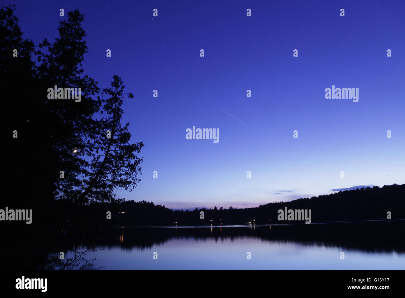 Paysage de nuit sur un lac de l'Ouest Vermont à avec Star Trails et une longue traînée de lumière à partir de la Station Spatiale ISS. Banque D'Images