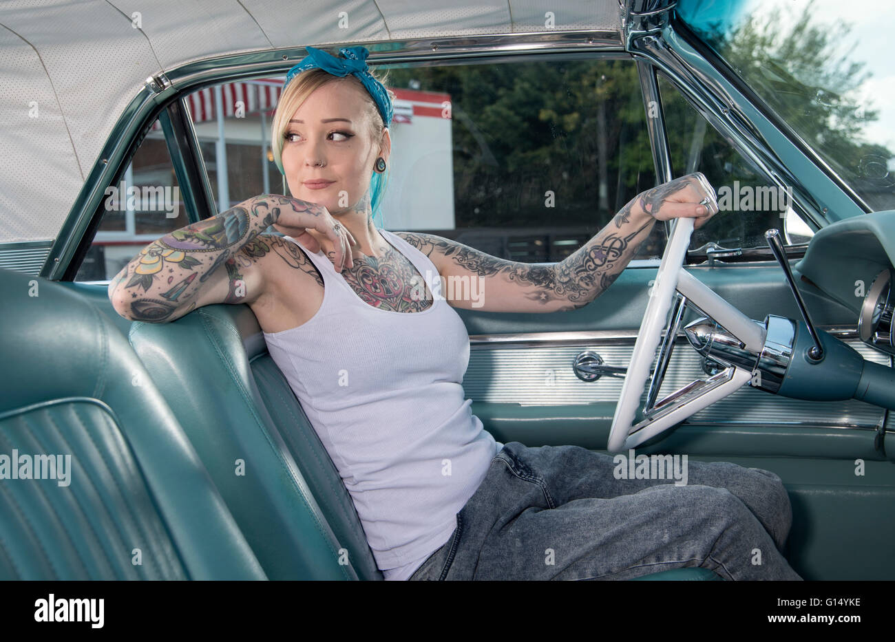 Fille tatouée en gang vêtements de style rétro dans une voiture américaine classique Banque D'Images