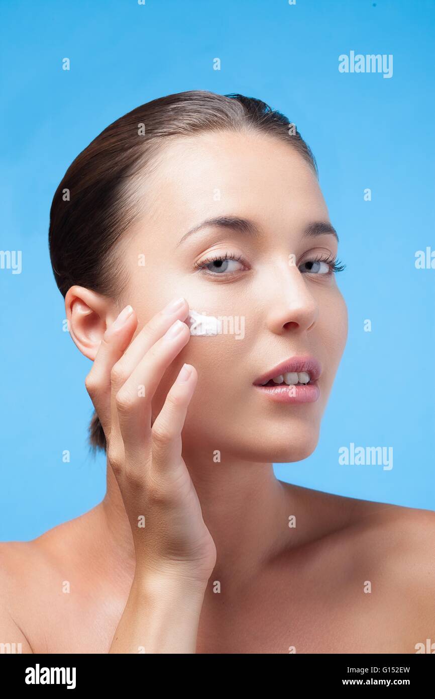 Jeune femme appliquer un hydratant sur son visage Banque D'Images