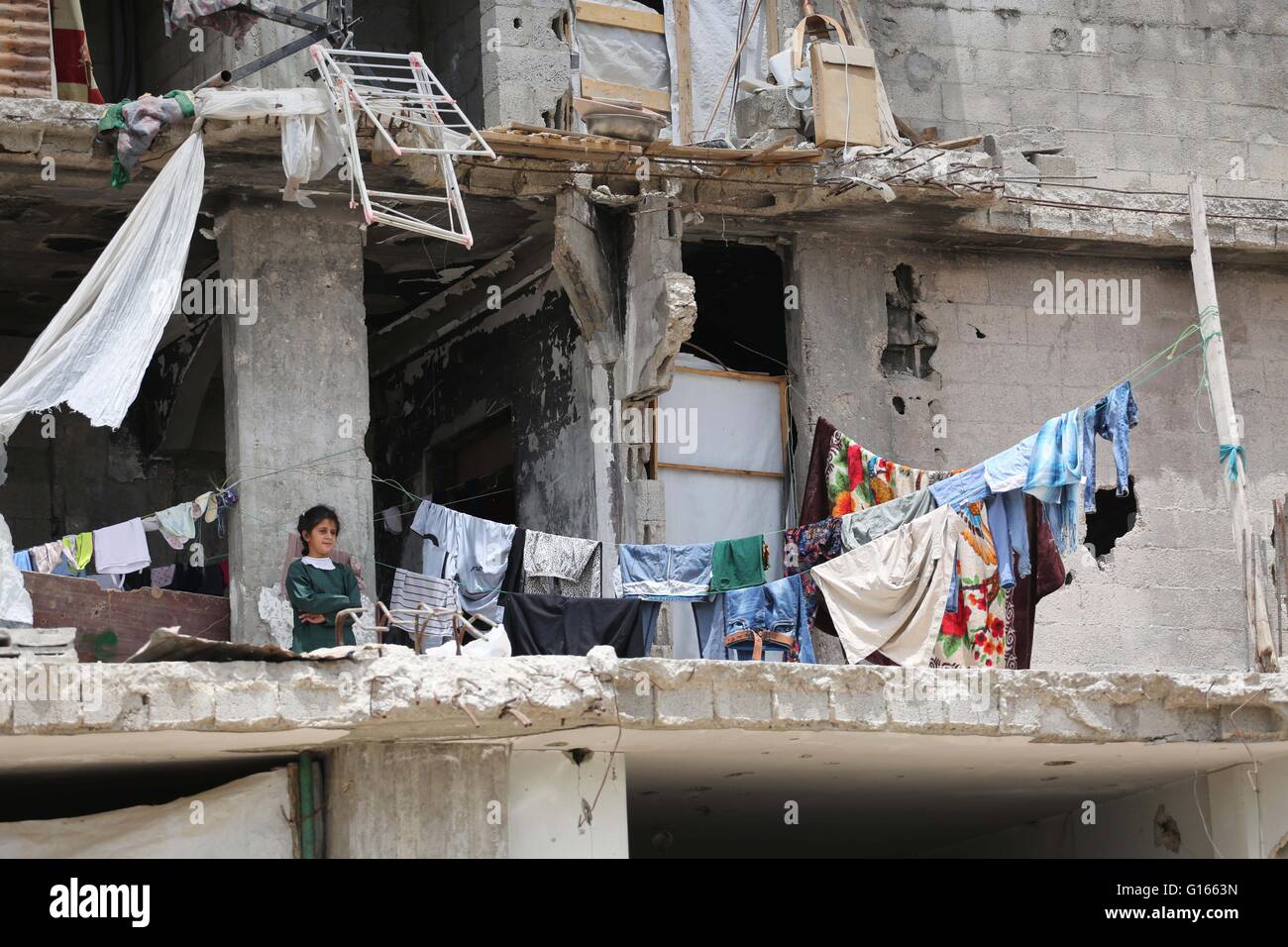 La ville de Gaza, bande de Gaza, territoire palestinien. 10 mai, 2016. Une fille palestinienne se trouve sur une maison détruite alors que le Ministre belge des Affaires étrangères Didier Reynders fait un discours dans le quartier de l'est de la ville de Gaza Shujaiya, qui a été détruit pendant la guerre de 50 jours entre Israël et le Hamas militants dans l'été de 2014, lors d'une visite officielle dans la bande de Gaza le 10 mai 2016 Crédit : Mohammed Asad APA/Images/ZUMA/Alamy Fil Live News Banque D'Images