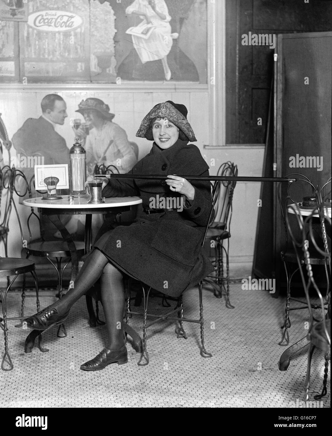 Flappers Races Femme assise à un soda fountain table est versé dans une tasse d'alcool ...