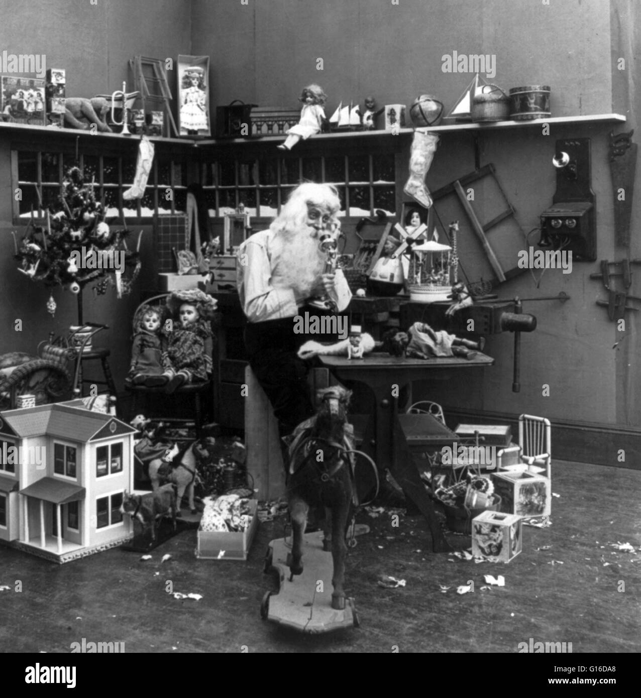 Intitulé : 'Santa dans son atelier à parler au téléphone et entouré de jouets." L'atelier du Père Noël où est le Père Noël est dit de faire les jouets et cadeaux remis à Noël. En plus d'accueillir l'usine où les jouets sont soit fabriqués ou dis Banque D'Images