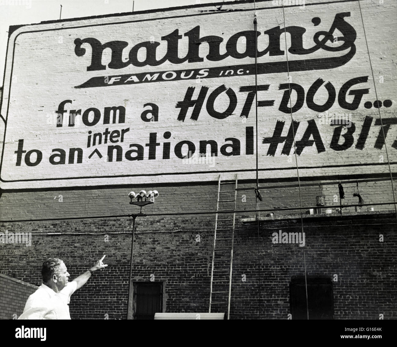 Intitulé : "d'un hot dog à un port international' montrant Nathan Handwerker pointant vers restaurant sign peint sur mur extérieur. Nathan's Famous, Inc. est une société américaine qui exploite une chaîne de restauration rapide spécialisée dans les hot-dogs. Nath Banque D'Images