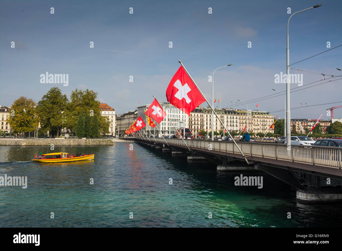 Vue du Pont Mont-Blanc à Genève avec drapeaux suisses et bateaux sur la rivière Rhône par temps clair, Suisse Banque D'Images