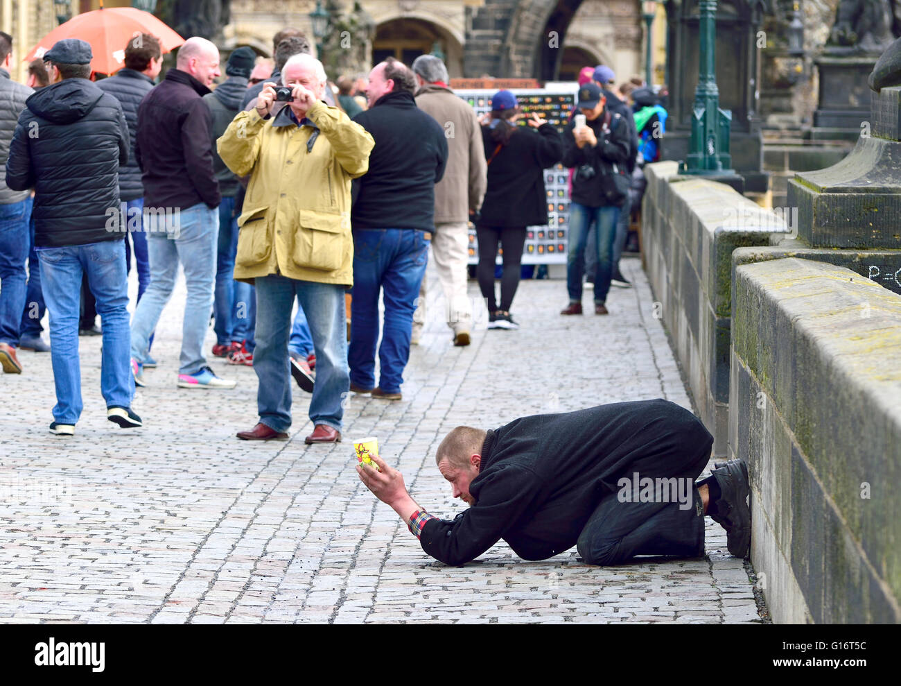Prague, République tchèque. Homme Postrate mendier sur le Pont Charles, les touristes passent devant Banque D'Images