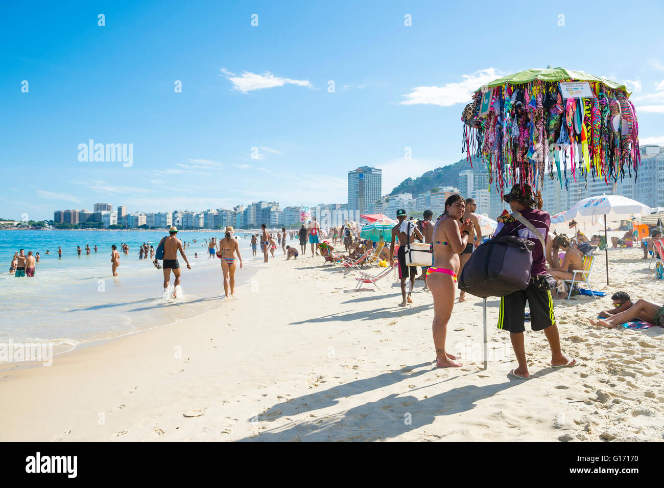 RIO DE JANEIRO - le 27 février 2016 : Les clients d'un vendeur parcourir bikinis sur la plage de Copacabana. Banque D'Images