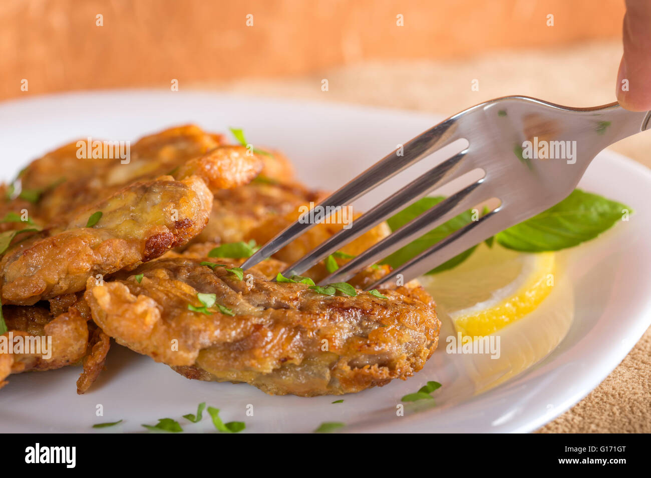 La consommation de porc frit avec du citron et herbes du cerveau on white plate Banque D'Images