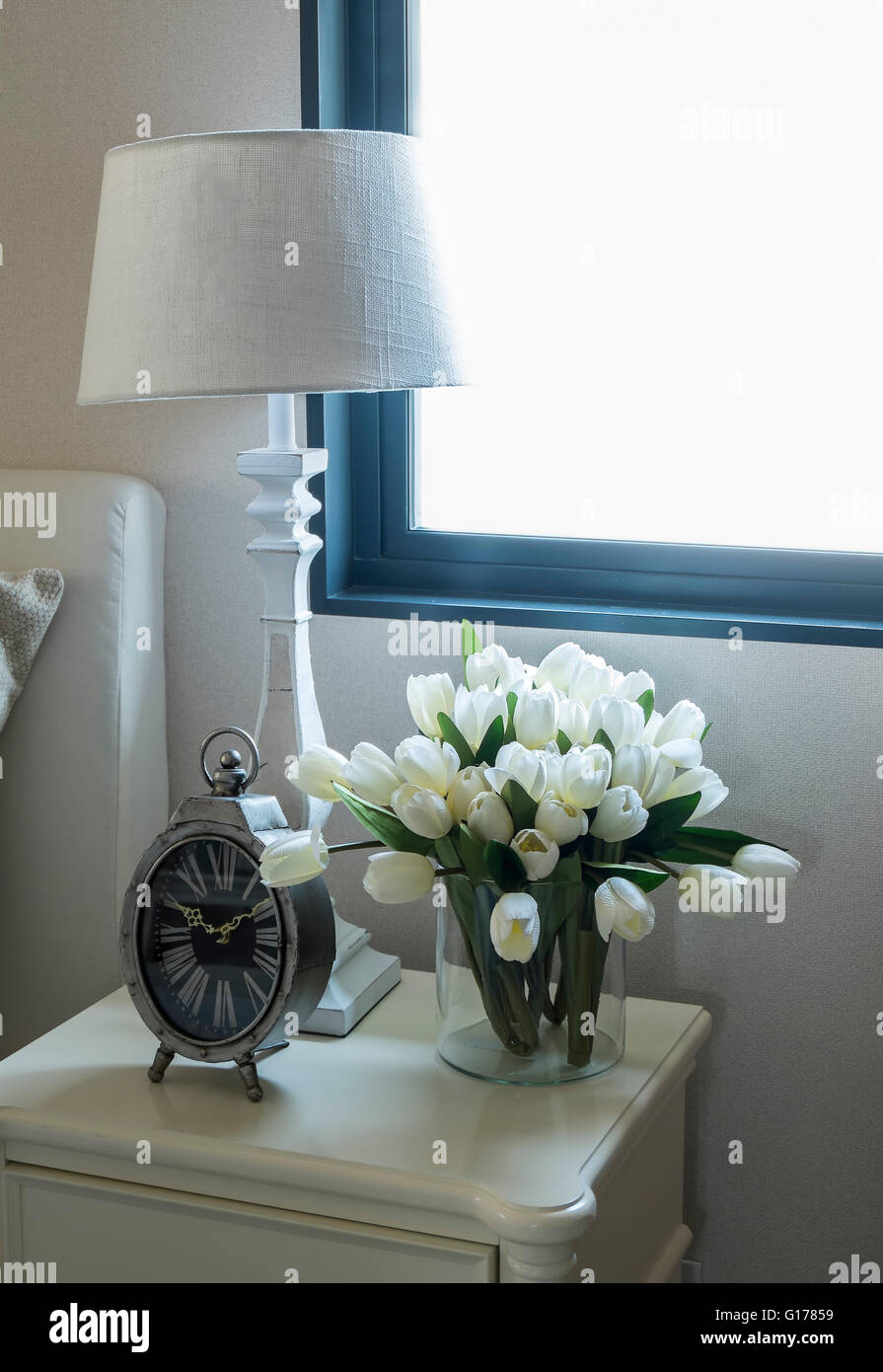 Lampe blanche et réveil sur la table de chevet Banque D'Images