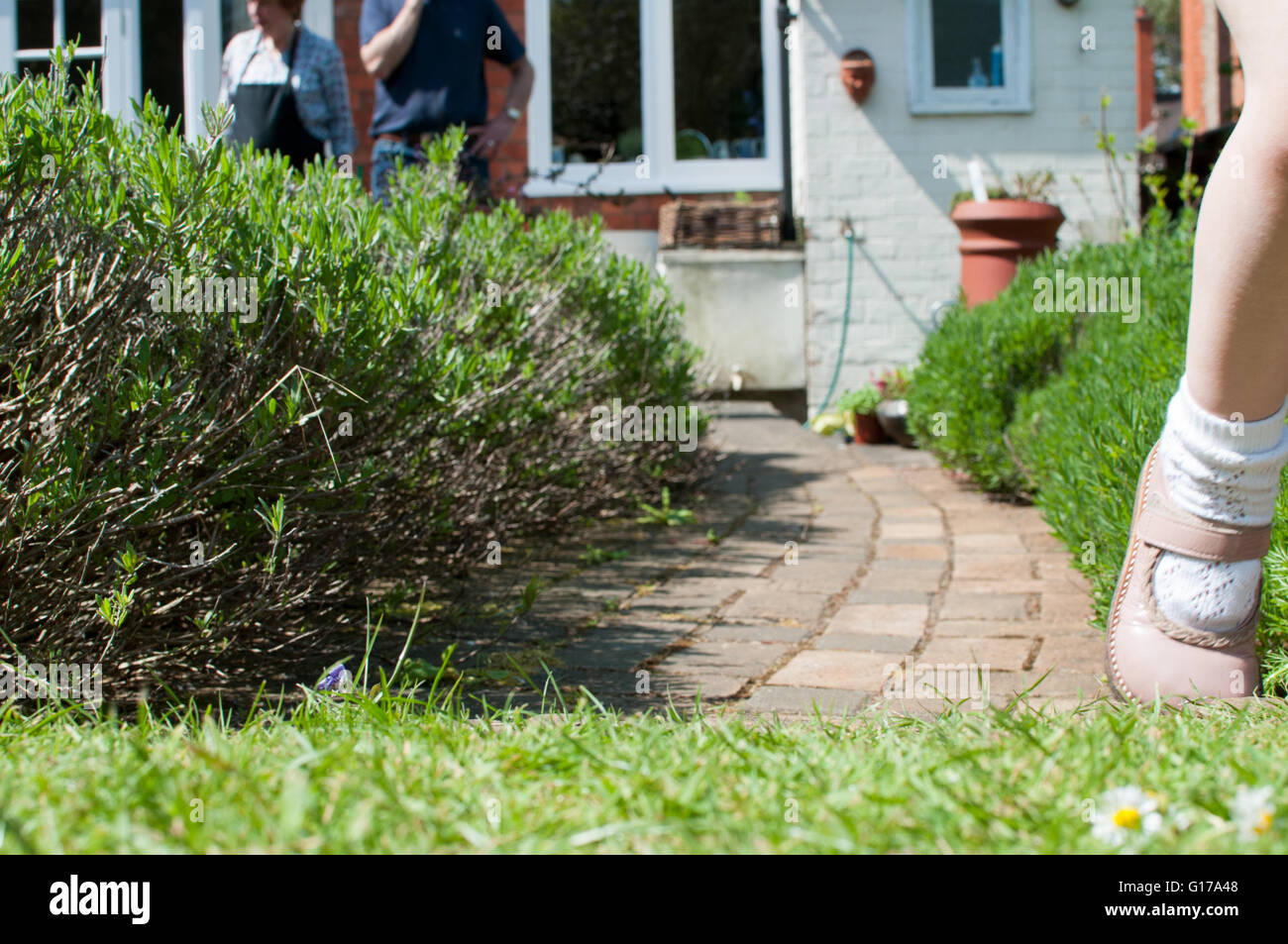 Les grands-parents l'observation d'un enfant jouer dans le jardin d'été Banque D'Images