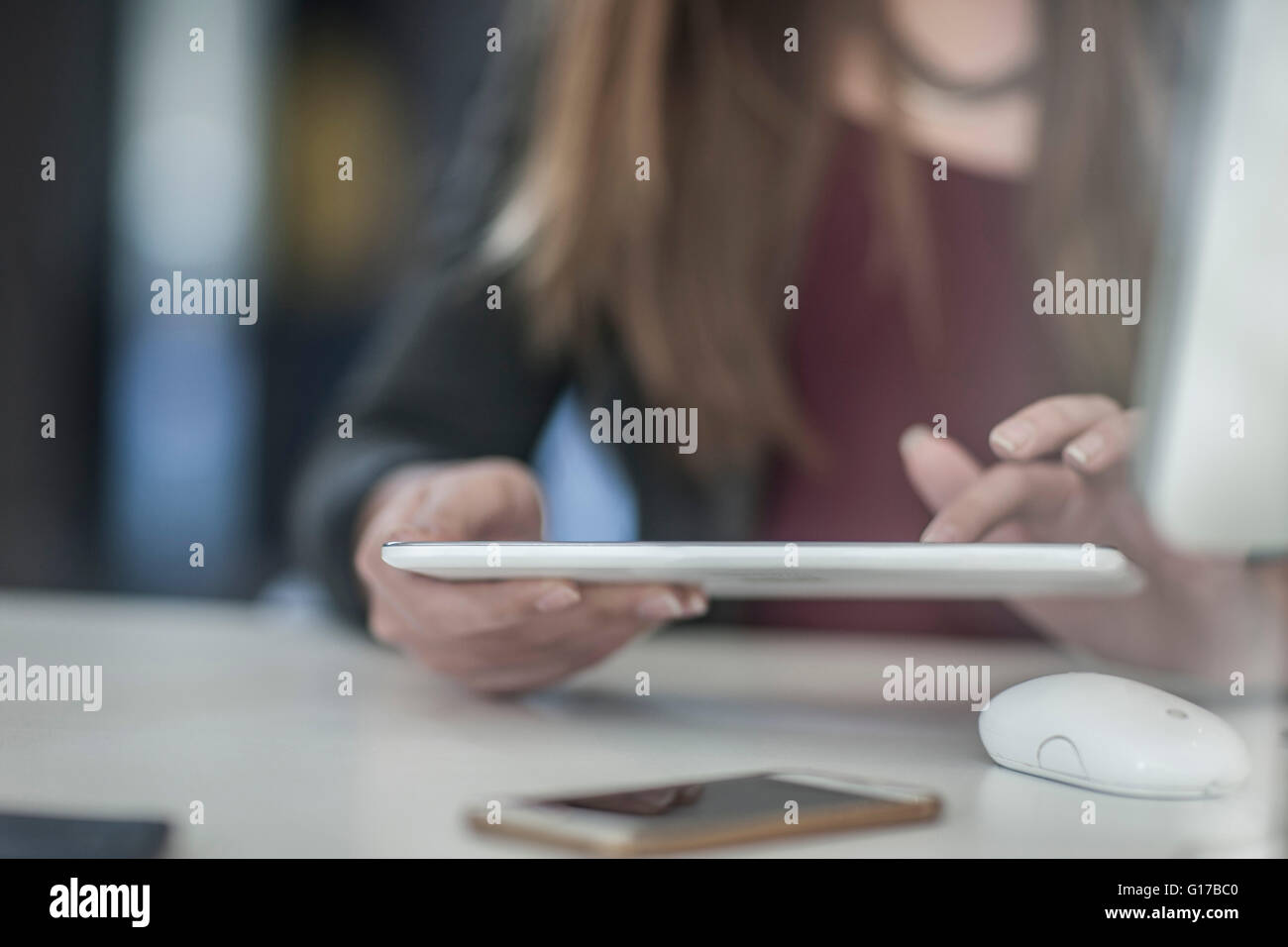 Businesswoman sitting at desk, using digital tablet, mid section Banque D'Images