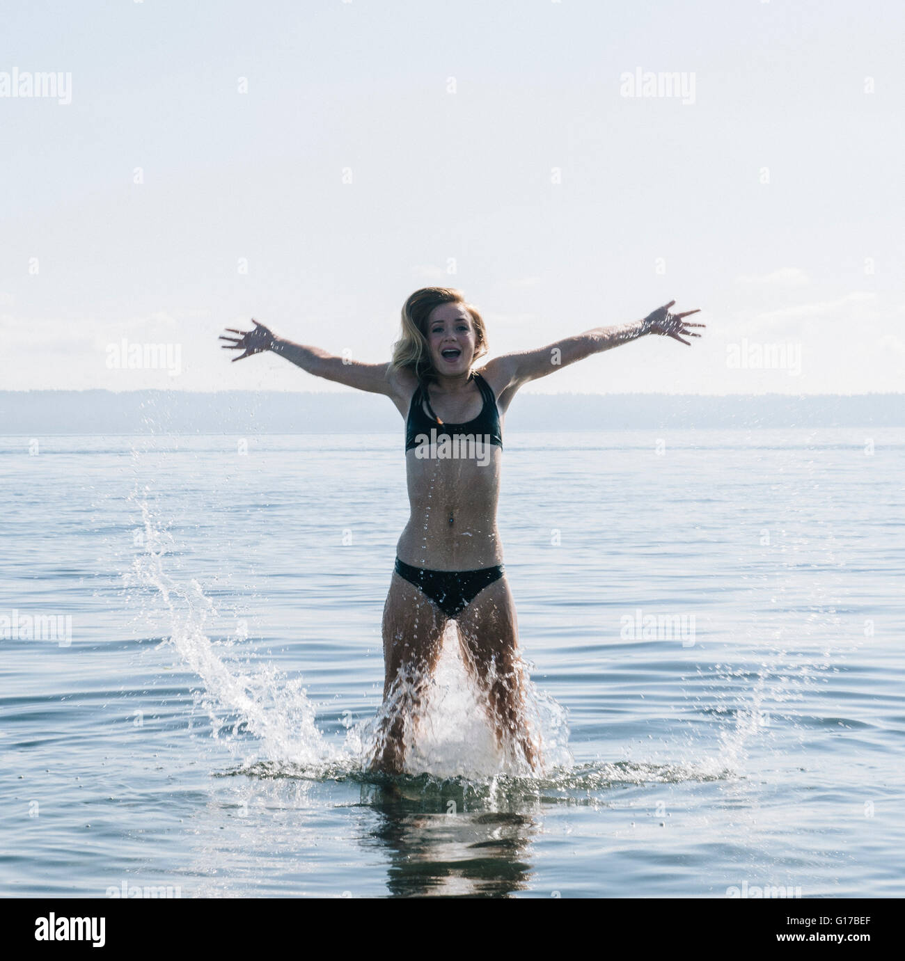 Teenage Girl standing en mer, les projections d'eau. Banque D'Images