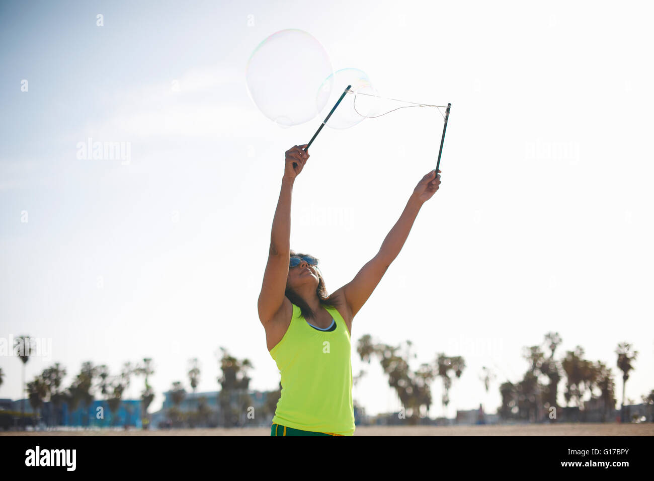 Femme, bras levés à l'aide de baguettes pour faire des bulles bulles Banque D'Images