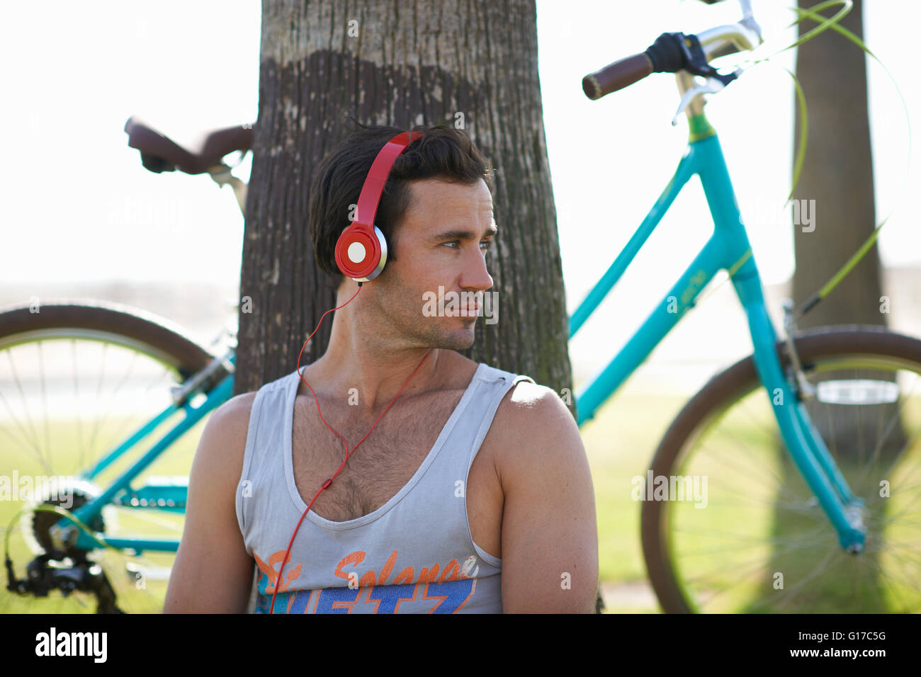 Cycliste homme assis à écouter la musique de casque à Venice Beach, Los Angeles, Californie, USA Banque D'Images