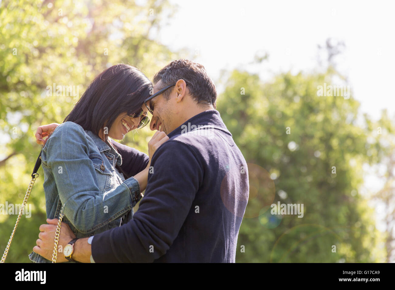 Couple in park face à face hugging and smiling Banque D'Images